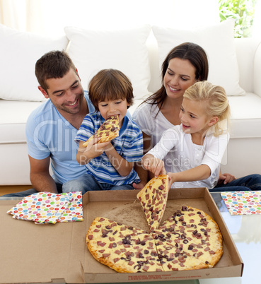 Young family eating pizza in living-room