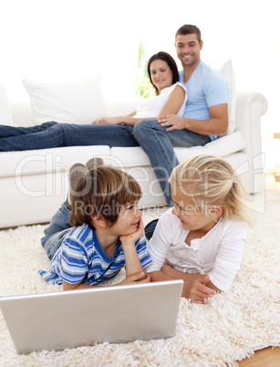 Friends using a laptop and couple on sofa