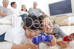 Children playing video games on floor and family on sofa