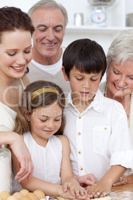 Grandparents looking at children baking in the kitchen