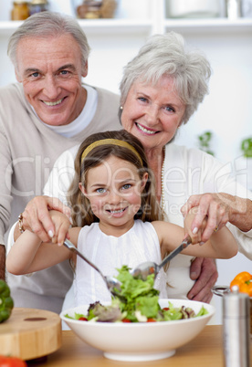 Smiling grandparents eating a salad with granddaughter
