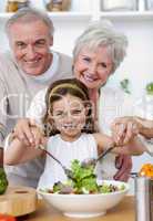 Smiling grandparents eating a salad with granddaughter