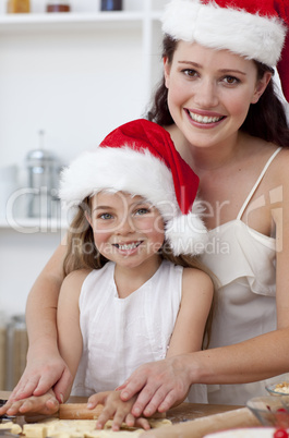 Smiling mother and daughter baking Christmas cakes