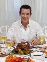 Smiling man eating turkey in Christmas dinner