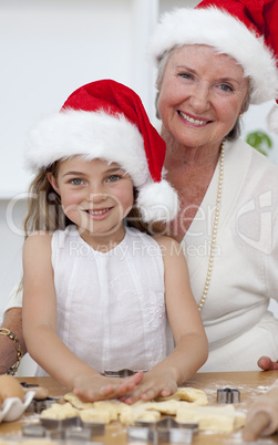 Smiling grandmother and little girl baking Christmas cakes