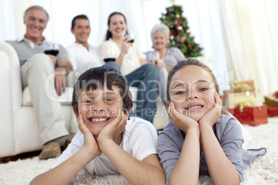 Brother and sister on floor with their family in Christmas