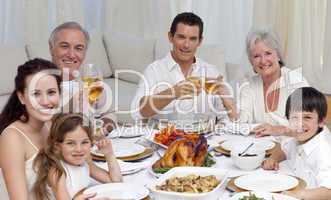 Family tusting with wine in a dinner smiling at the camera