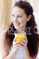 Portrait of woman drinking orange juice in bedroom