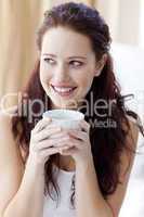 Beautiful woman drinking a cup of coffee in bed
