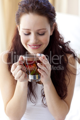 Beautiful woman drinking a cup of tea in bedroom