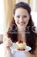 Smiling woman eating a sweet dessert