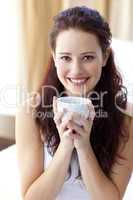 Beautiful woman drinking a cup of coffee in bedroom