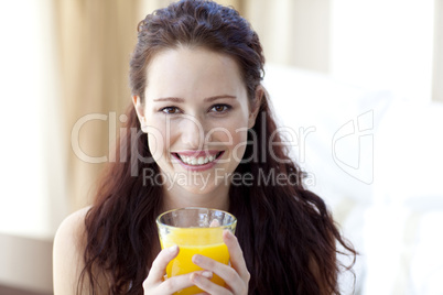 Girl drinking orange juice in bedroom