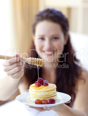 Woman holding pancakes with fruit and honey