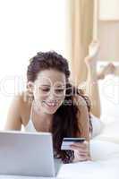 Beautiful woman lying in bed shopping online