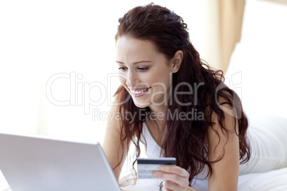 Beautiful woman on bed with a laptop and credit card