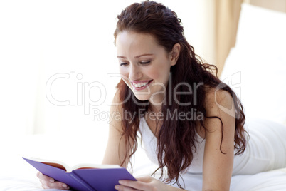 Beautiful woman reading a book in bed