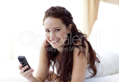 Smiling woman sending a text in bed