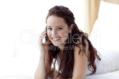 Smiling woman in bed talking on phone