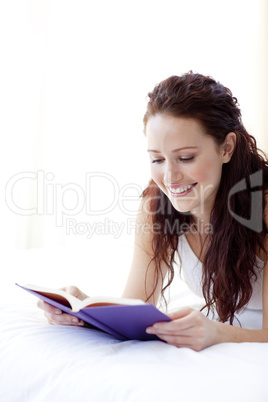Happy woman reading a book in bed