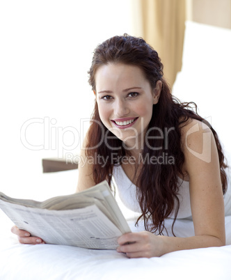 Beautiful woman in bed reading a newspaper