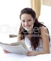 Beautiful woman in bed reading a newspaper