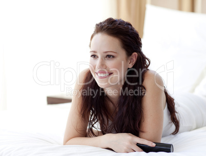 Beautiful woman lying in bed watching television