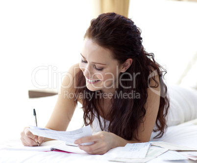 Smiling woman writing notes in bed