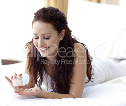 Beautiful woman in bed taking pills