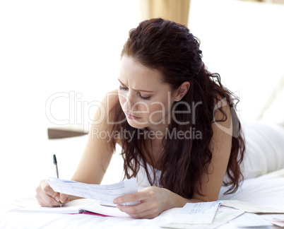 Concentrated woman writing notes in bed