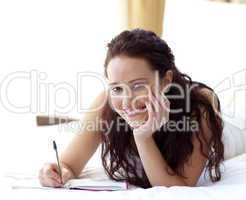 Beautiful woman writing notes in bed