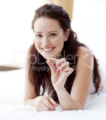 Woman in bed holding a pill