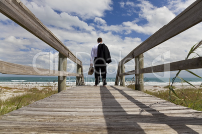 Businessman Standing Barefoot Looking Across A Beach To The Sea