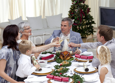 Family tusting in a Christmas dinner with champagne