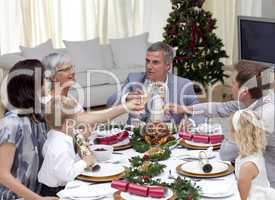 Family tusting in a Christmas dinner with champagne