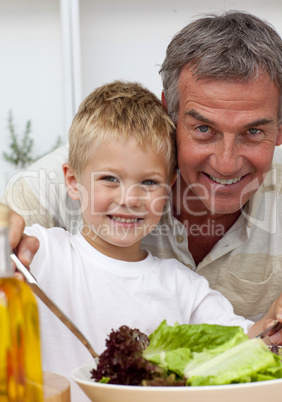 Happy grandfather cooking a salad with grandson