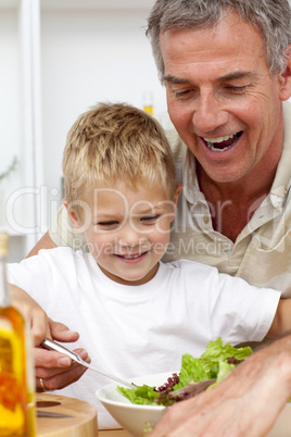Happy grandfather eating a salad with grandson