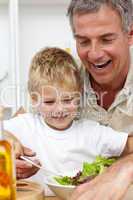 Happy grandfather eating a salad with grandson