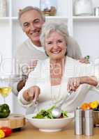 Happy senior couple eeating a salad in the kitchen