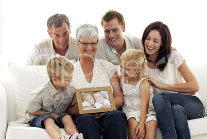 Happy family holding a portrait of children sitting on sofa