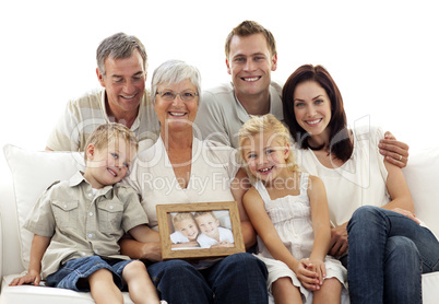 Family holding a portrait of children sitting on sofa