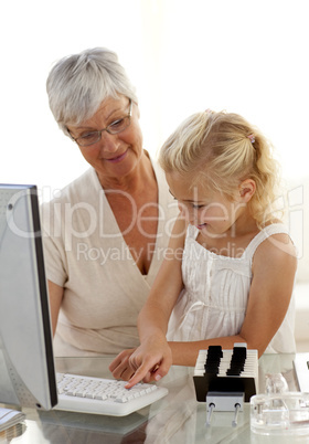 Granddaughter explaining her grandmother how to use a computer