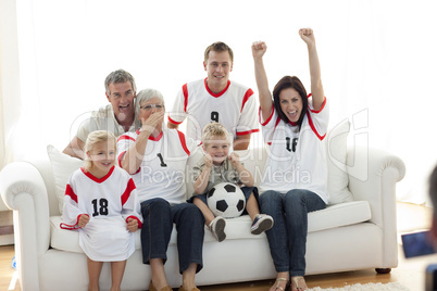 Happy family watching a football match in television