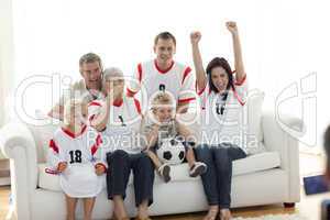 Happy family watching a football match in television