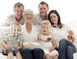 Family watching television and eating chips at home