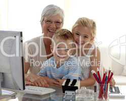 Happy children using a computer with their grandmother