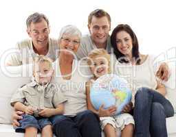 Big family on sofa holding a terrestrial globe