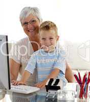 Happy grandson using a computer with his grandmother