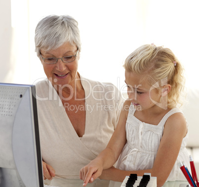Little girl explaining her grandmother how to use a computer