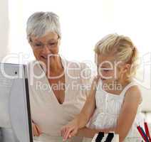 Little girl explaining her grandmother how to use a computer